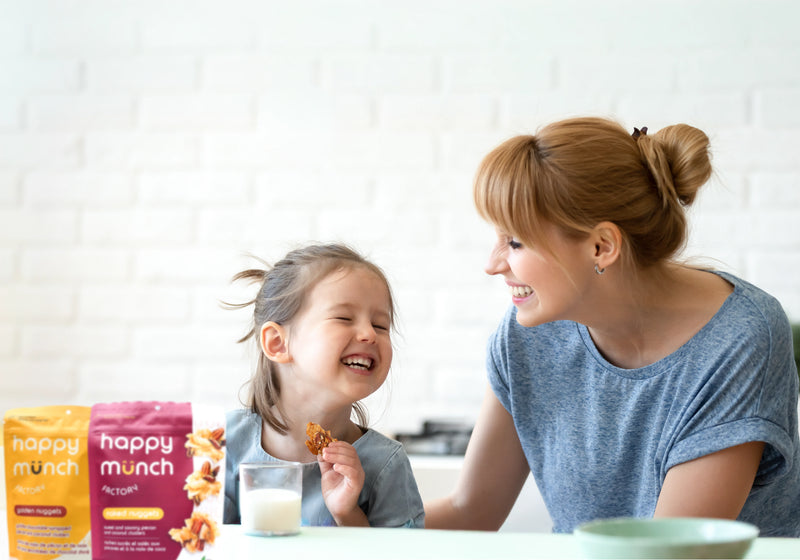Woman and child enjoying snacks with 'happy munch' packaging in the foreground.