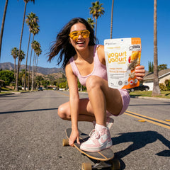A girl on a skateboard holding Mango Mania Yogurt Clusters.