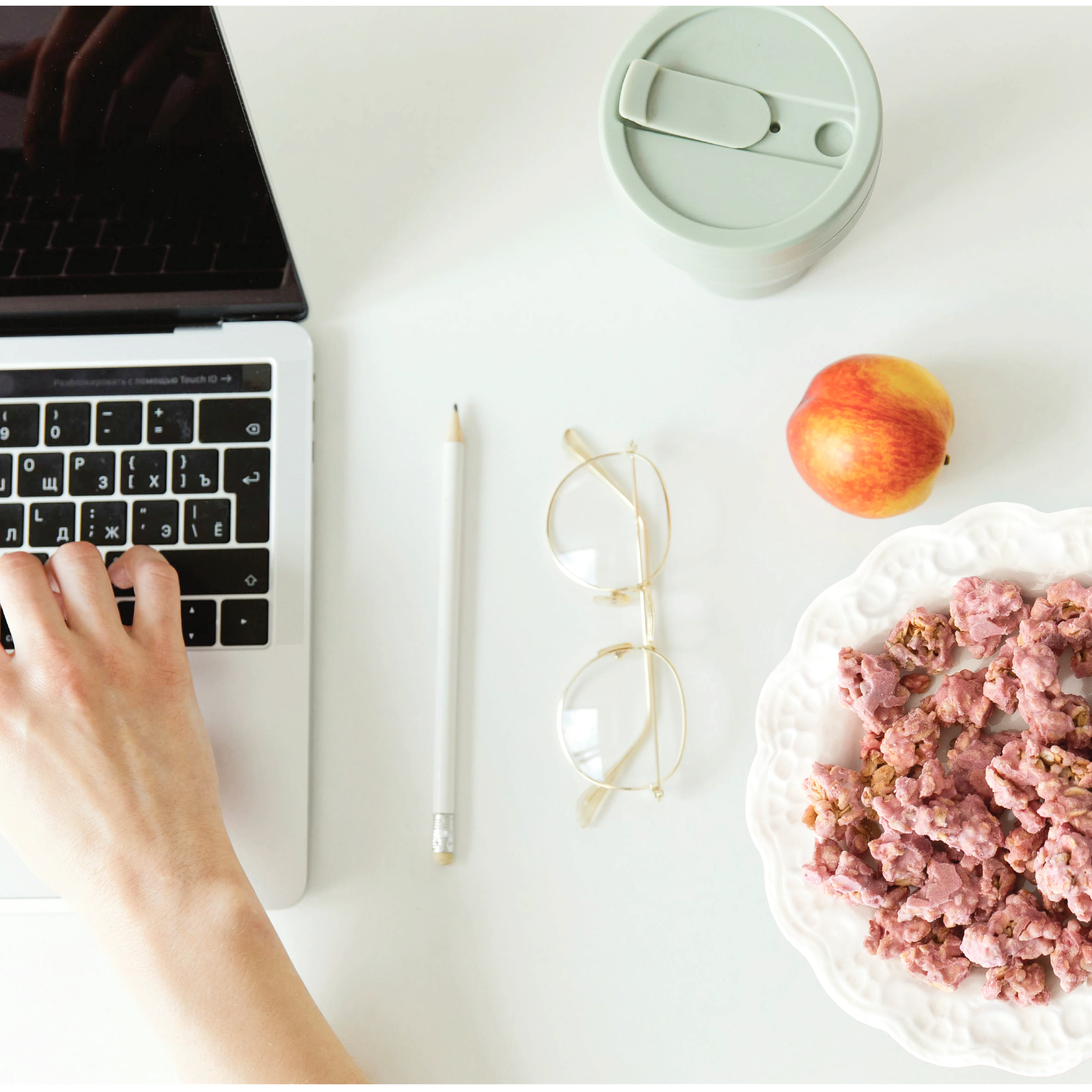 Person using a laptop on a desk with Happy Munch Yogurt Cluster Strawberry splash, an apple, and glasses