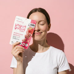 A woman holding the Strawberry Splash Yogurt Cluster against a pink wall