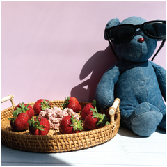 Blue teddy bear with sunglasses next to a basket of strawberries and Happy Munch Strawberry Splash